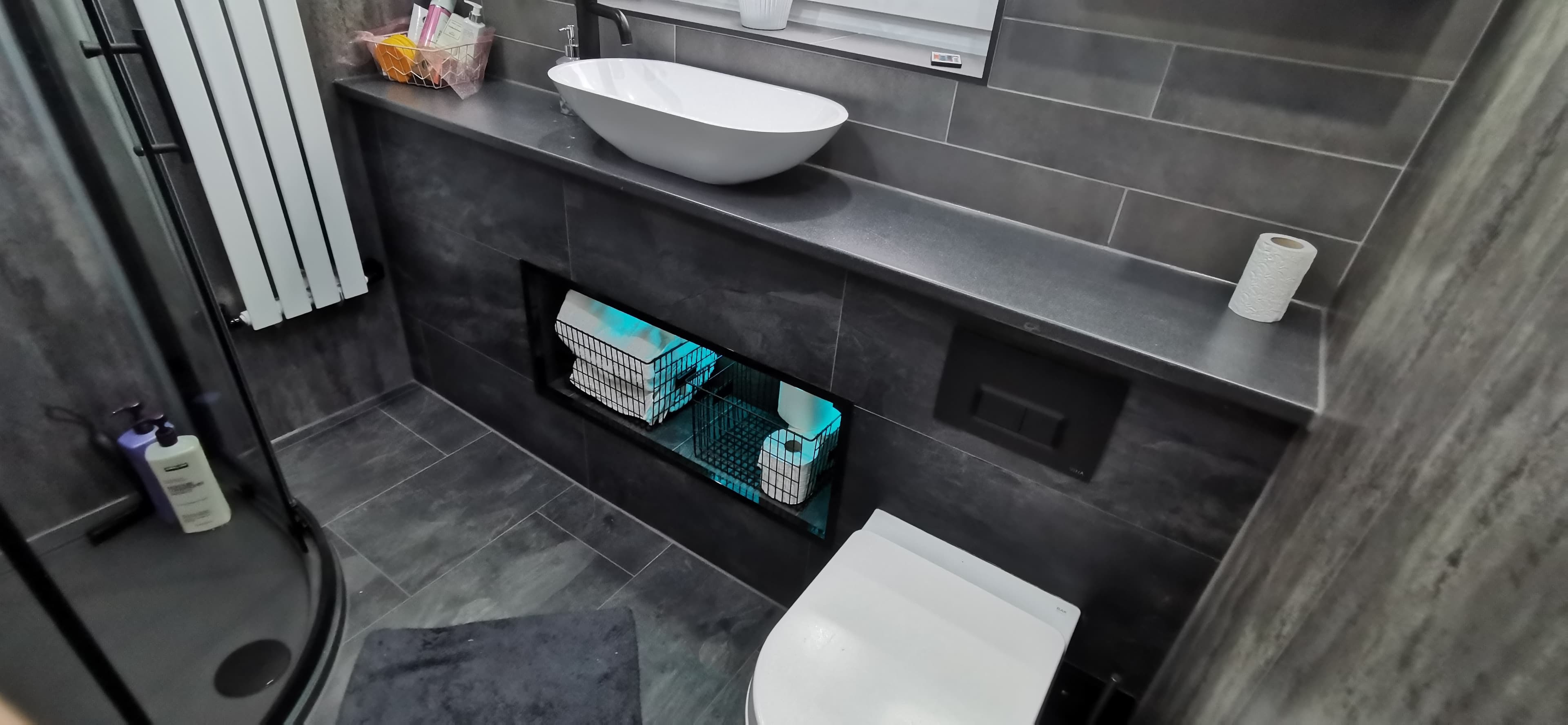 Backlit mirror cabinets either side of the window in a finished bathroom